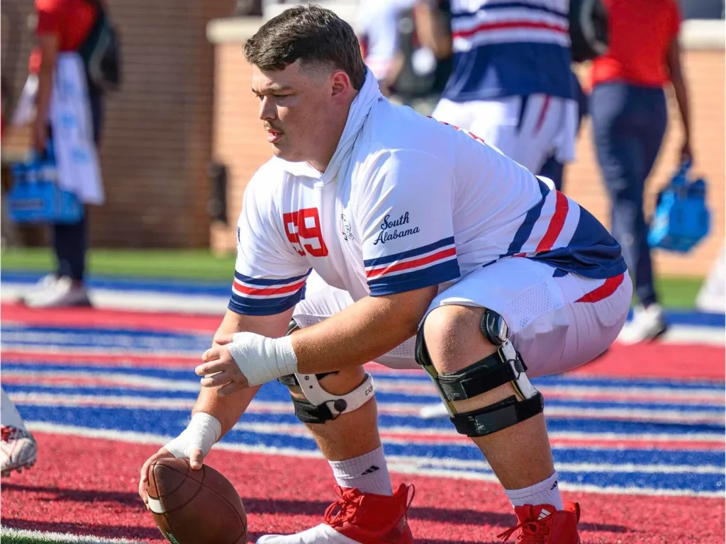 Sam in a three-point stance on the field in a South Alabama jersey